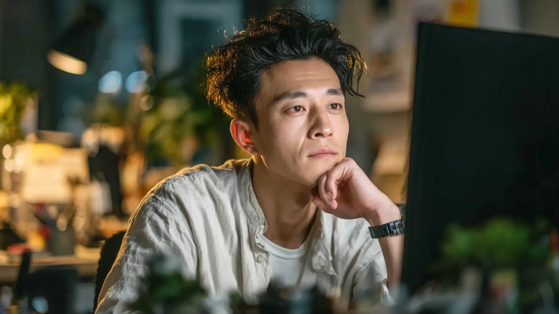 A website designer thinking in front of his computer monitor about customization