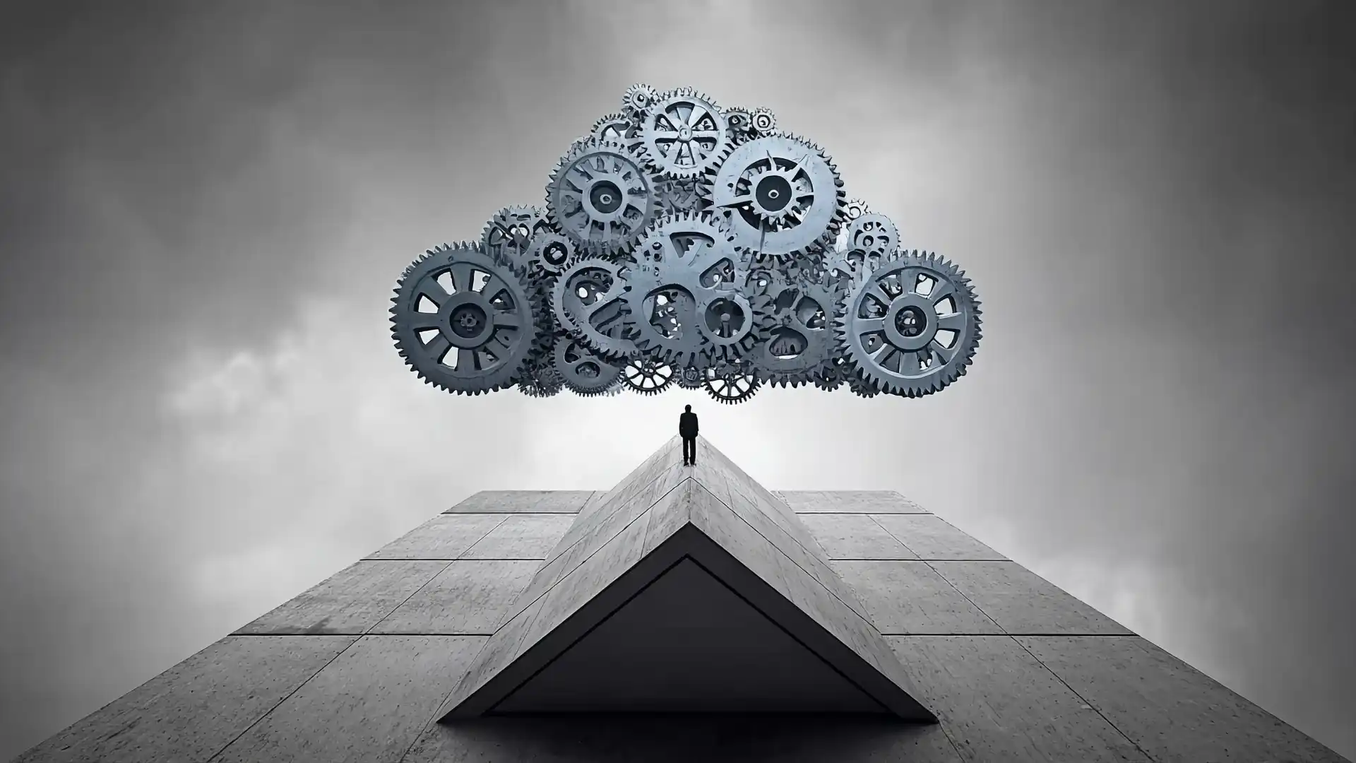 A futuristic image of a businessman standing under a floating group of cogs
