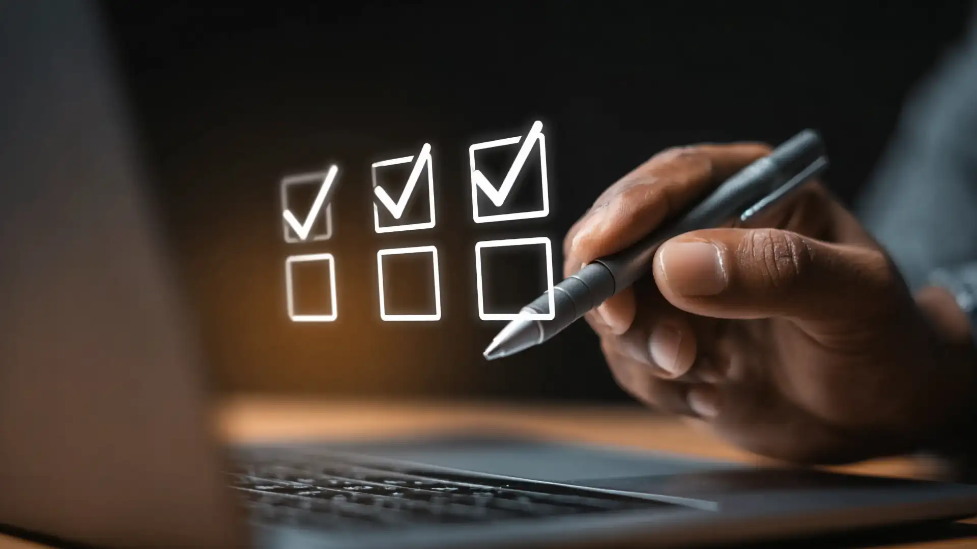 A photo of a hand holding a stylus pen checking floating boxes in front of a laptop screen